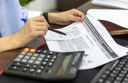 Analista conferindo uma conta de energia com calculadora sobre a mesa