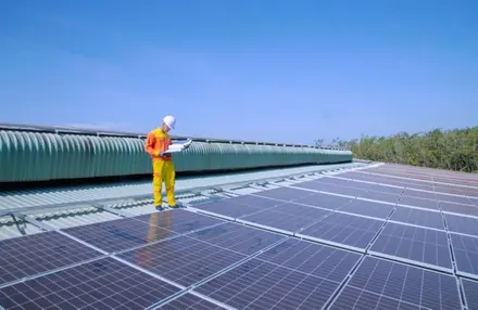 Técnico com prancheta inspecionando módulos solares na cobertura