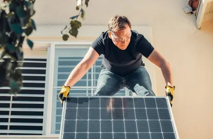 Instalador posicionando um módulo fotovoltaico no telhado