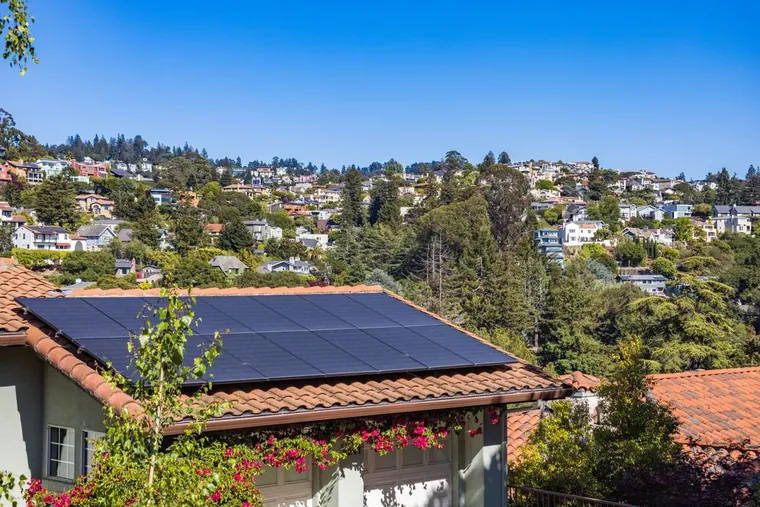 Painéis solares no telhado de uma residência cercada por vegetação