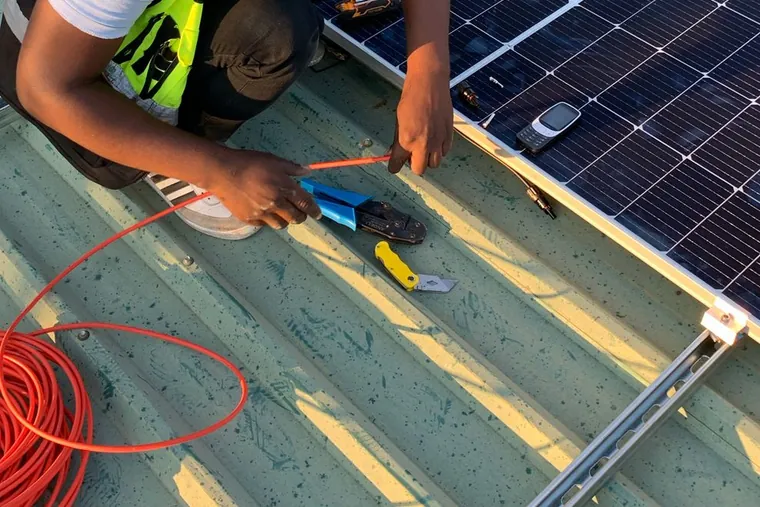 Técnico conectando cabos de um sistema fotovoltaico